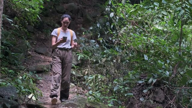 Female explorer looking for connection to the internet or using gps navigator app on smartphone in green forest