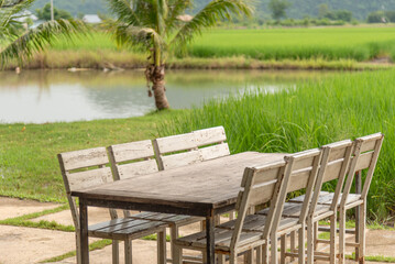 Fototapeta premium Wooden dinning table set in the greensward at garden and lake fore relaxing in vacation