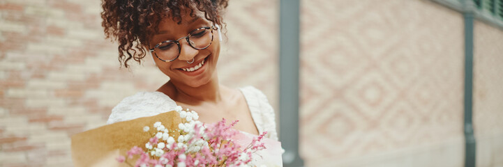 young woman in glasses walks with a bouquet of flowers along the street of the old city and listens...