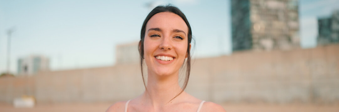 Portrait of young athletic woman with long ponytail wearing beige sports top on sandy city beath