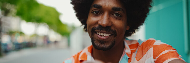 Close-up frontal portrait of cheerful young African American man wearing shirt smiling at the...