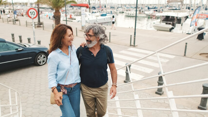 Happy middle aged couple, retired elderly couple enjoy outdoor recreation together, hugging each other, talking on yachts background
