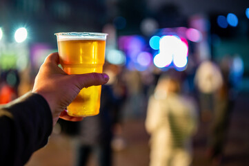 plastic cup glass with beer in hand. Outdoor summer festival