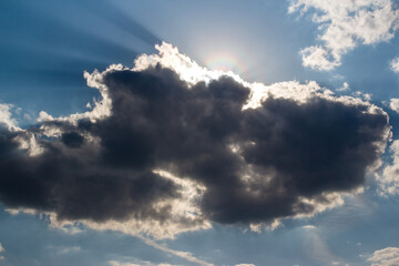 The sun hidden behind a cloud in the blue sky