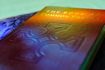 Church of Ireland Book of Common Prayer, lit by light from a stained glass window, resting on a...
