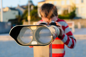 Boy in striped top looks through binoculars/telescope