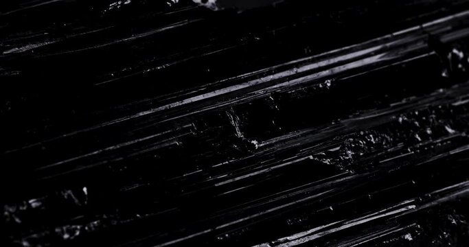 Schorl black tourmaline with moving light in 4k. macro detail texture background. close-up raw rough unpolished semi-precious gemstone
