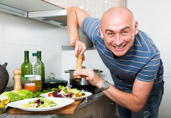 Ordinary man sprinkle with pepper salad on plate