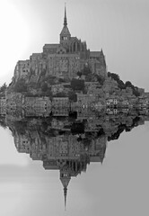 Reflection on the water during high tide of Mont Saint Michel abbey in Northern France with black...