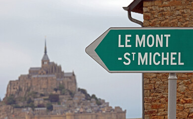 Road sign with arrow and the famous Mont Saint Michel abbey in France