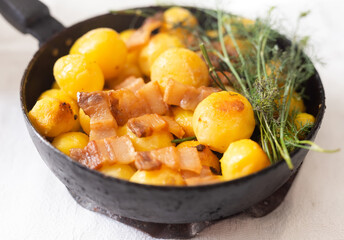 Young potatoes with pork belly fried in frying pan