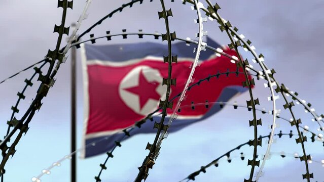 Barbed wire, flag of North Korea in defocus, sky background with clouds, 3d render. Concept: international sanctions, totalitarian regime, repression of people, closed state.