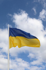 big waving Ukrainian flag with yellow and blue color and clouds with sky