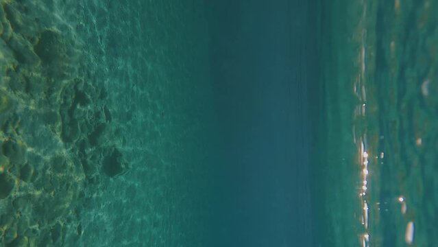 POV underwater shot, man swims rowing his hands under surface of blue water