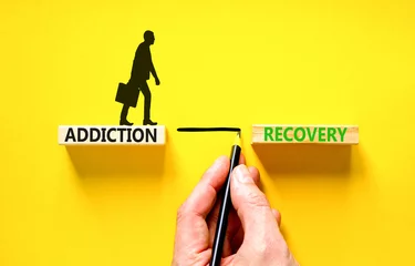 Poster Addiction recovery symbol. Concept words Addiction recovery on beautiful wooden blocks. Psychologist icon. Beautiful yellow table yellow background. Psychology addiction recovery concept. Copy space. © Dzmitry