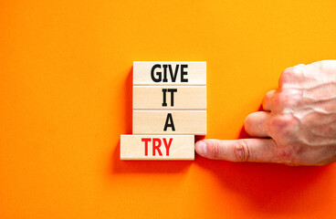 Give it a try symbol. Concept word Give it a try on beautiful wooden block. Beautiful orange table orange background. Businessman hand. Business give it a try concept. Copy space.