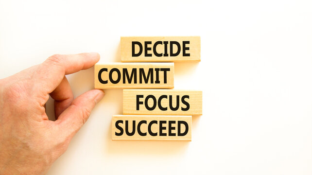 Decide commit focus succeed symbol. Concept word Decide Commit Focus Succeed on wooden block. Beautiful white background. Businessman hand. Business decide commit focus succeed concept. Copy space.