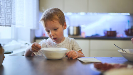 A child stirring hot soup at the table.