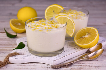 Sweet and sour creamy lemon dessert in a glass on a white background.