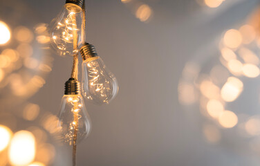 Banner with three LED-bulbs surrounded by blurred lights hanging on a rope. Space for text. Warm,...