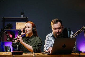 Couple of bloggers in headphones broadcasting live video, broadcasting on air, using sound studio...