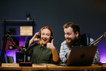 Couple of bloggers in headphones broadcasting live video, broadcasting on air, using sound studio...