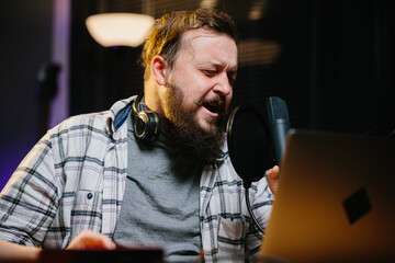 Portrait of a radio presenter or blogger in a home studio. A man in headphones speaks expressively...