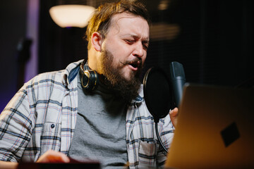 Portrait of a radio presenter or blogger in a home studio. A man in headphones speaks expressively...