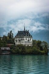 Fototapeta na wymiar Vertical of the historical castle Seeburg in Switzerland surrounded by the teal lake Brienz