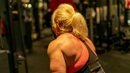 Fit blonde female with toned muscles working out arms at the gym