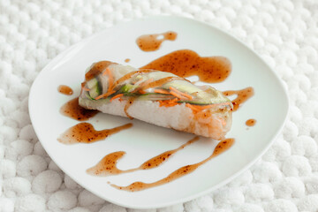 Spring rolls and spicy sauce on white background. Summer rolls with fresh vegetables and shrimps and peanut sauce. Vietnamese appetizer. Salad spring rolls with prawns. Healthy food concept. 