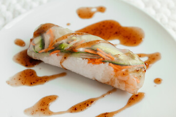 Spring rolls and spicy sauce on white background. Summer rolls with fresh vegetables and shrimps and peanut sauce. Vietnamese appetizer. Salad spring rolls with prawns. Healthy food concept. 