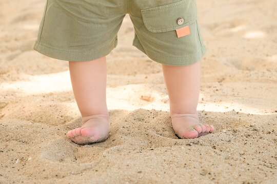 Tiny baby toddler feet on the sand beach close up with copy space