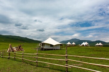 Green landscape and mountains with white tent houses placed on the meadow