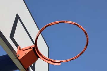 Closeup of a basketball hoop with not net on a blue sky background