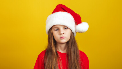 Upset little girl wearing Christmas costume standing isolated over yellow background wall in studio