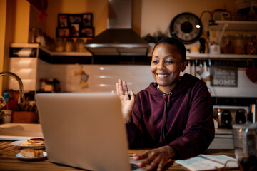 Woman waving hand and saying hello while having video call at home