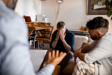 Male gay couple having couple therapy with professional at home