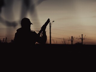 Silhouette of a soldier holding a gun during sunset