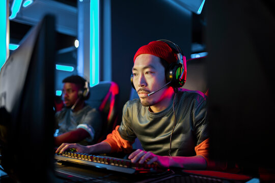 Concentrated Asian Gamer Playing in a High-Stakes Esports Tournament