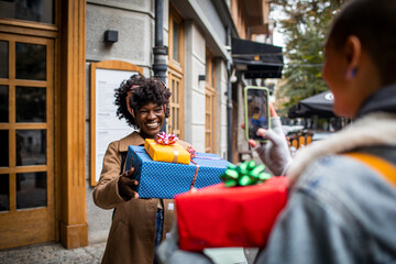 Smiling woman holding present posing for picture in the city