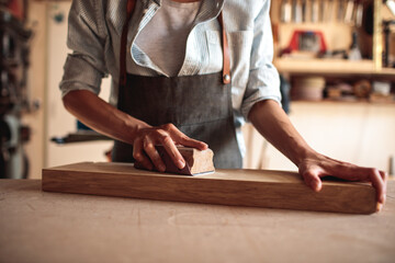 Young Female Artisan Carpenter Sanding Wood in a Workshop