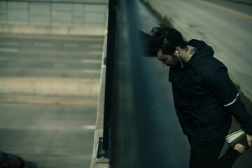 Young man in sport clothes warming up stretching before jog outdoors