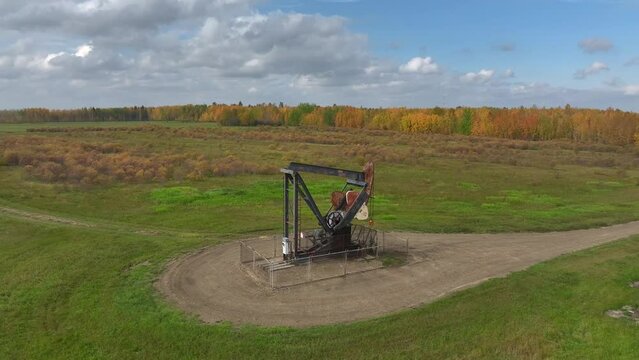 Solitary oil well in northern Alberta, Canada on a sunny autumn day on a rural dirt road drone video