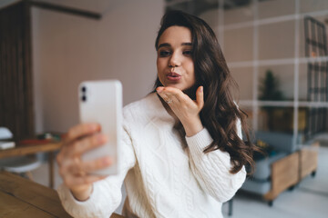 Smiling woman standing with smartphone in living room
