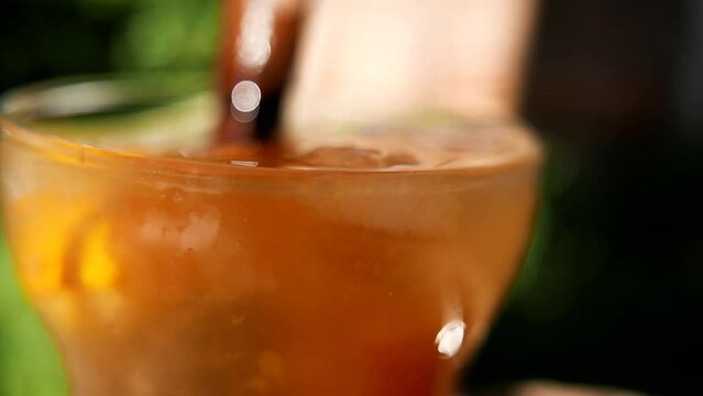 Making a Caipirinha. Close-up shot of a person muddling a Caipirinha. Stirring a tangerine Caipirinha. Using a wooden muddler. A tangerine caipirinha with cacha&ccedil;a (sugarcane liquor), sugar and ice.