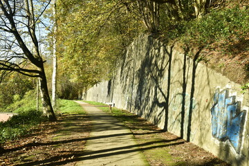 Chemin le long d'un vieux mur en pierres parfois couvert de tags près de la gare de Morlanwelz 