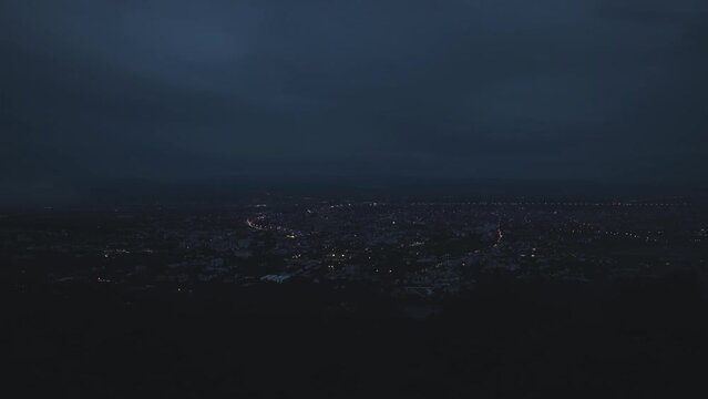 Time-lapse of the mist drifted over the city in the evening before it fade away. Fog over the city, city in fog. Zoom out.