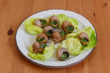 Escargots de Bourgogne (snails) seasoned with butter, parsley, garlic on wooden table