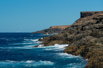 Fototapeta na wymiar Beautiful landscape with deep blue water. Powerful waves crash against black volcanic rocks on the coast of ´Aguas Verdes, Fuerteventura island.